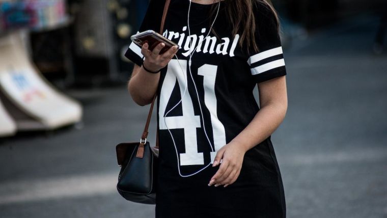 Girl wearing black sports shirt looking at mobile phone.