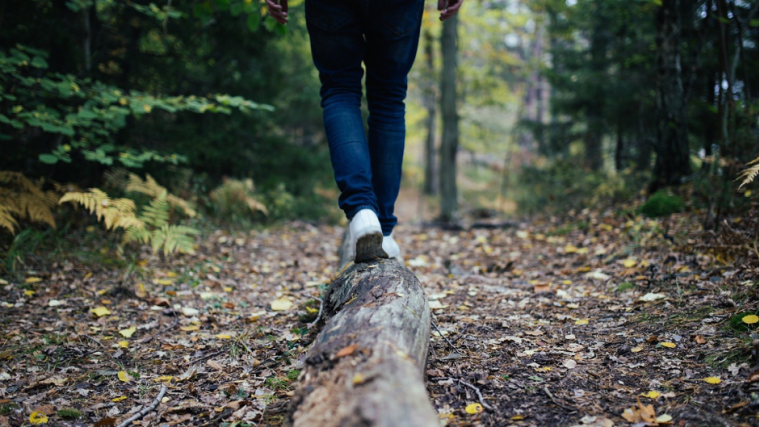 Woman walking away across a log in the forest