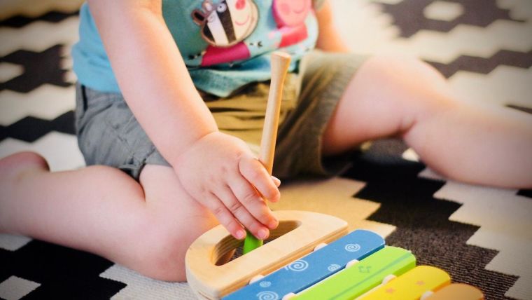 Young child sitting on the floor next to a xylophone